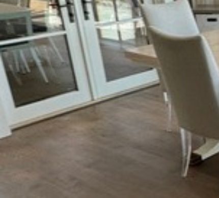 Gray-brown hardwood plank floor in a dining area by French doors by The Hardwood Guys, serving Fairfield, CT